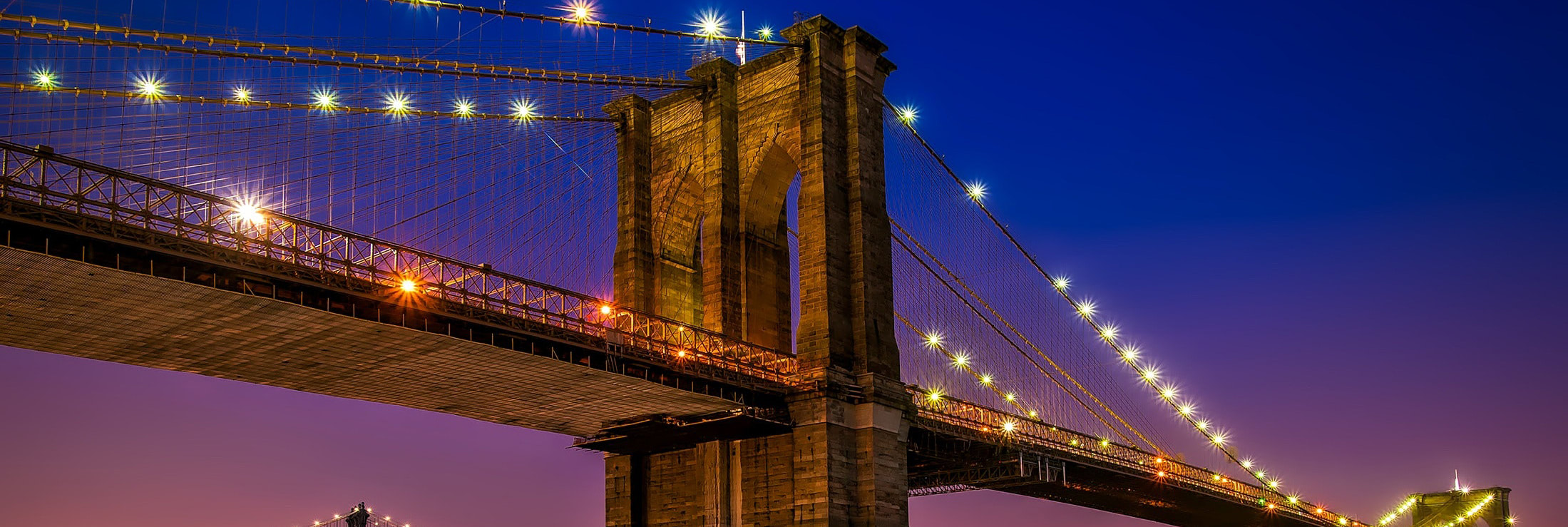 The Brooklyn Bridge illuminated at night, the inspiration for Power Magnetics’ durability motto